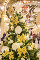 Decorations of GUM mall during winter holidays. White porcelain tea cups and saucers with golden ribbons on green fir