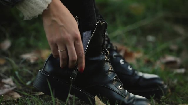 Woman unfasten zip on boots, take off shoes