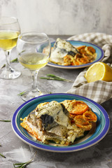 Slices of mackerel with carrot. A restaurant. Glasses of white wine. Rosemary seasoning. Place for text. Decor with lemon. Gray background.