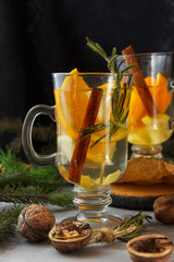 Winter ginger tea with orange and lemon in glass cups. Cinnamon and Rosemary Spices  Decor with Christmas tree branches and cones. Christmas composition.