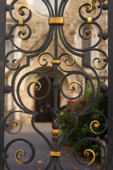 Ornamented gold painted metal gate with old chapel seen behind