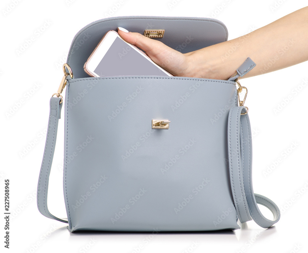 Wall mural a hand put the phone in the female blue gray leather handbag on a white background isolation