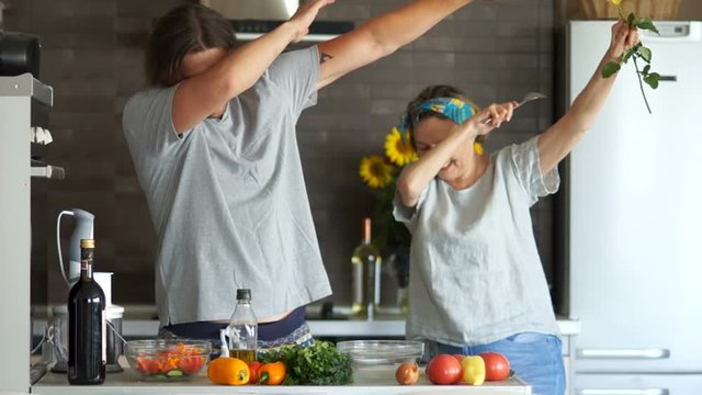 Debbing son and mother. Happy family dancing in the kitchen. Modern kitchen interior. Mother and son jokingly dance while cooking dinner
