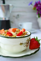 Sunny Sunday morning breakfast served outdoor in summer garden with fresh natural yogurt and strawberry