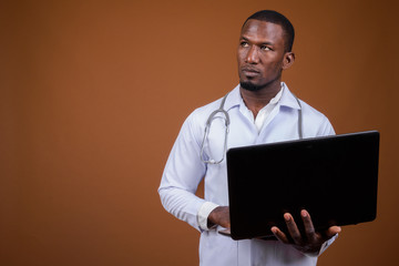 Handsome African man doctor against brown background