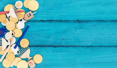 Hanukkah dreidels with Menorah and some Hanukkah coins and candles on a vintage wood background....