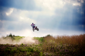 Obraz premium Biker performing stunt in mid air against cloudy sky
