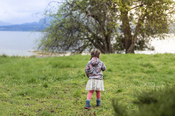 little girl in floral jacket outside in the park with scenic landscape and mpountains in the horizon