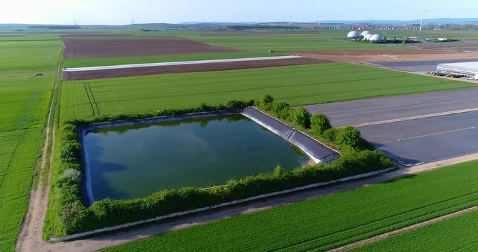 Technical reservoir next to large greenhouses, green fields around a large greenhouse, Technical reservoir around a large greenhouse