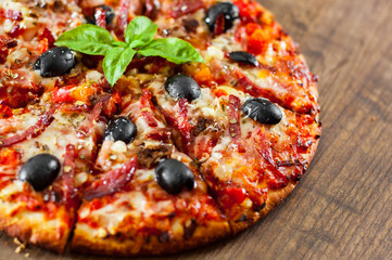 slices of Pizza with Mozzarella cheese, salami, pepper, ham, pepperoni, olives, Spices and Fresh Basil. Italian pizza on wooden background