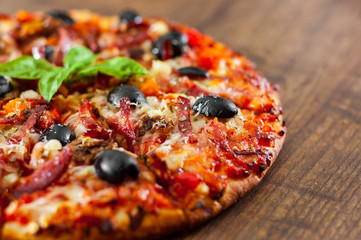 slices of Pizza with Mozzarella cheese, salami, pepper, ham, pepperoni, olives, Spices and Fresh Basil. Italian pizza on wooden background