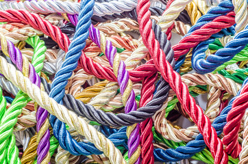 Decorative multicolored cords of ropes scattered in a chaotic manner. Textile industry, thread, decoration