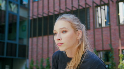 A young girl performs modern hip hop dance on the streets of the city during the summer, twisting and rotating.