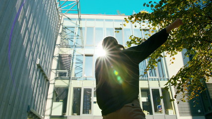 A young girl performs modern hip hop dance on the streets of the city during the summer, twisting...