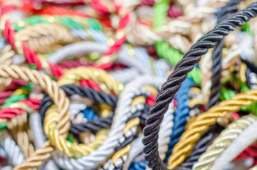 Multi-colored braided decorative laces scattered in a mess. Textile manufacture, threads, decor.