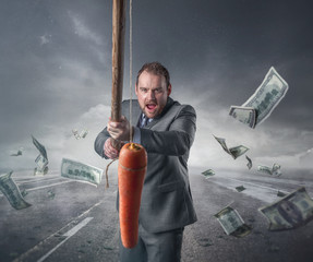 Businessman holding a carrot in a stick