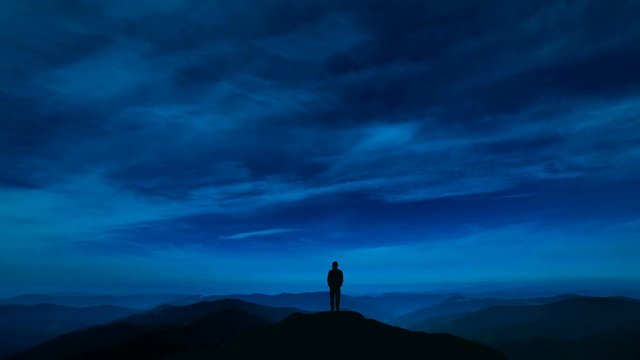 The man standing on a night mountain with a cloud stream. time lapse