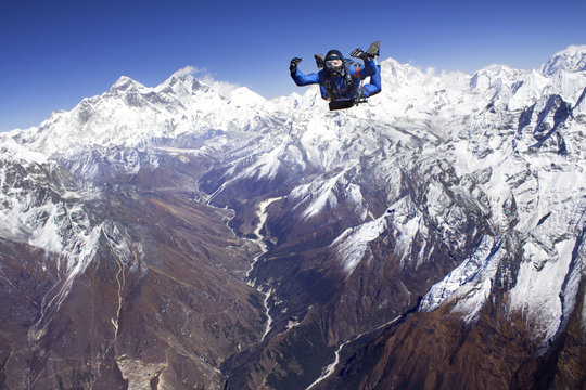 Man skydiving against snowcapped mountains