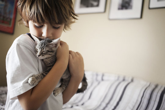 Boy carrying cat at home