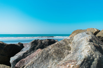 Fototapeta na wymiar Rocks on shore looking at beach horizon during day
