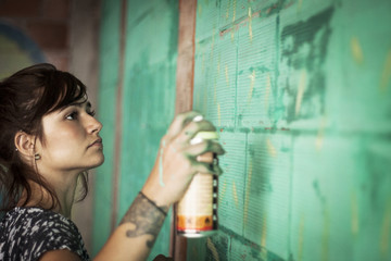 Woman spraying graffiti on wall © Cavan for Adobe