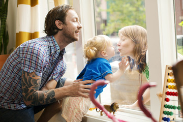 Obraz premium Father holding daughter while looking at mother through window