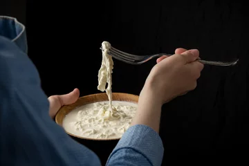 Zelfklevend Fotobehang Zuivelproducten Woman in blue apron holding bowl with stracciatella mozzarella cheese on dark background