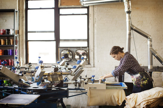 Woman making print on t shirt in workshop