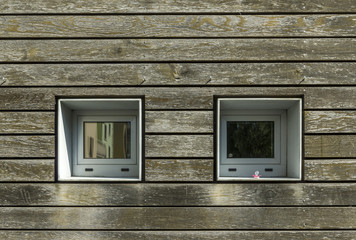 Fassade Ausschnitt mit Holzverkleidung und zwei quadratischen Fenstern mit Schnuller  Hintergrund,...