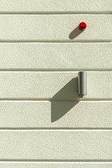 Fassade Wohnhaus Verputz mit horizontalen Fugen, Edelstahlleuchte rotes Notfalllicht, Detail Facade...