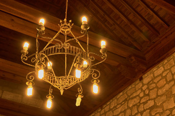 Close-up from inside the church with lighted lamps and .roof with wooden beams in the background in Las Ventas con Peña Aguilera, Toledo, Spain