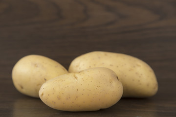 three potatoes on brown background
