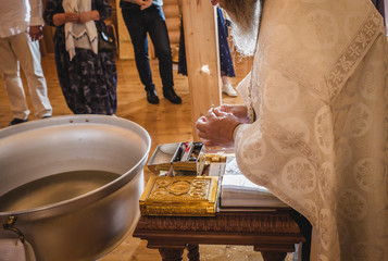 Christening ceremony in the Orthodox church, priest lighting candles at children baptismal font, close up