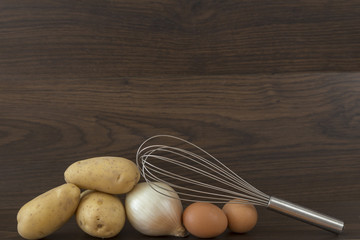 potatoes, onion and egg on brown background