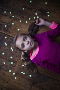 Overhead view of girl lying on wooden floor surrounded with stars