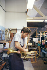 Man shaping trumpet in workshop © Cavan for Adobe