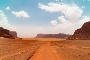 Wadi Rum desert, Jordan, Middle East, known as The Valley of the Moon. Orange sand, blue sky, haze and clouds. Designation as a UNESCO World Heritage Site. Red planet Mars landscape.