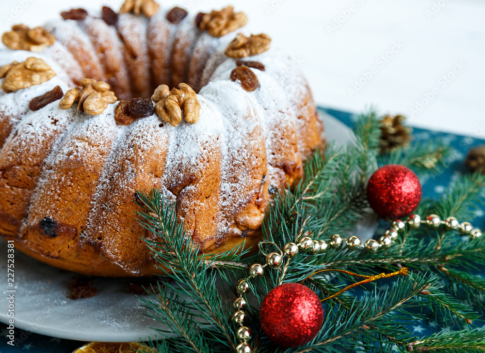 Wall mural Traditional fruitcake for Christmas decorated with powdered sugar and nuts, raisins. Delicioius Homemade Pastry. New year and Christmas celebration concept