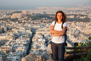 woman sitting on Lycabettus Hill, the highest point in the city overlooking Athens with the Acropolis - world traveller