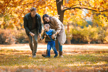 Young family having fun in the autumn park with his son.