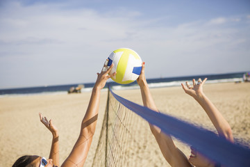 Obraz premium Friends playing beach volleyball on sunny day