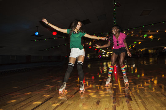 Friends enjoying roller skating at illuminated roller rink