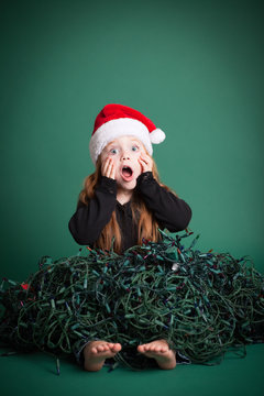 Stressed Christmas Girl In Tangled Lights, Isolated On Green