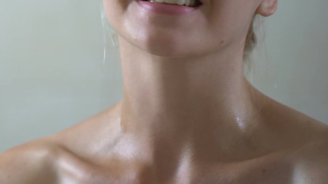 Smiling woman applying perfume on neck in bathroom, special scent for lady