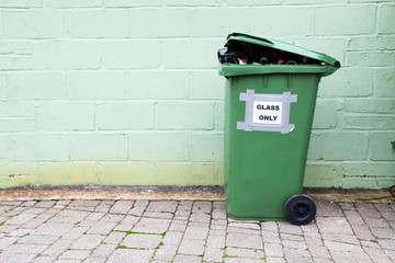 Green glass bottle recycling bin against a green wall background