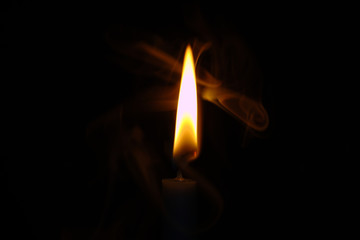 Glowing Orange and White Candle Flame With Swirling Wisps of Smoke Centered Against a Black Background
