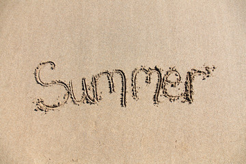 Fototapeta na wymiar The word 'summer' written on sand on a beach 