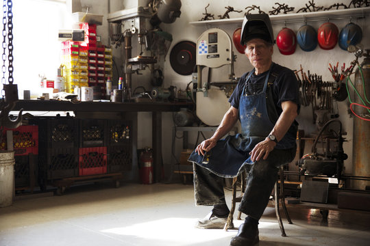 Portrait of senior man sitting on chair in workshop