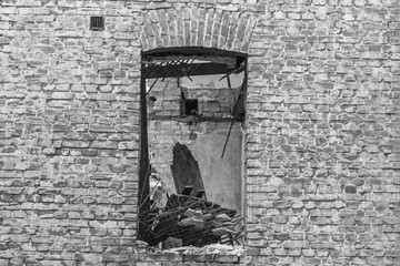 Brick wall with a window. Old house. Destroyed building. Empty window opening. cityscape. Old and new building. City building. Masonry. Ruins on the site of a residential building.