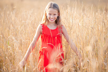 Beautiful little blonde girl, has happy fun cheerful smiling face, red dress